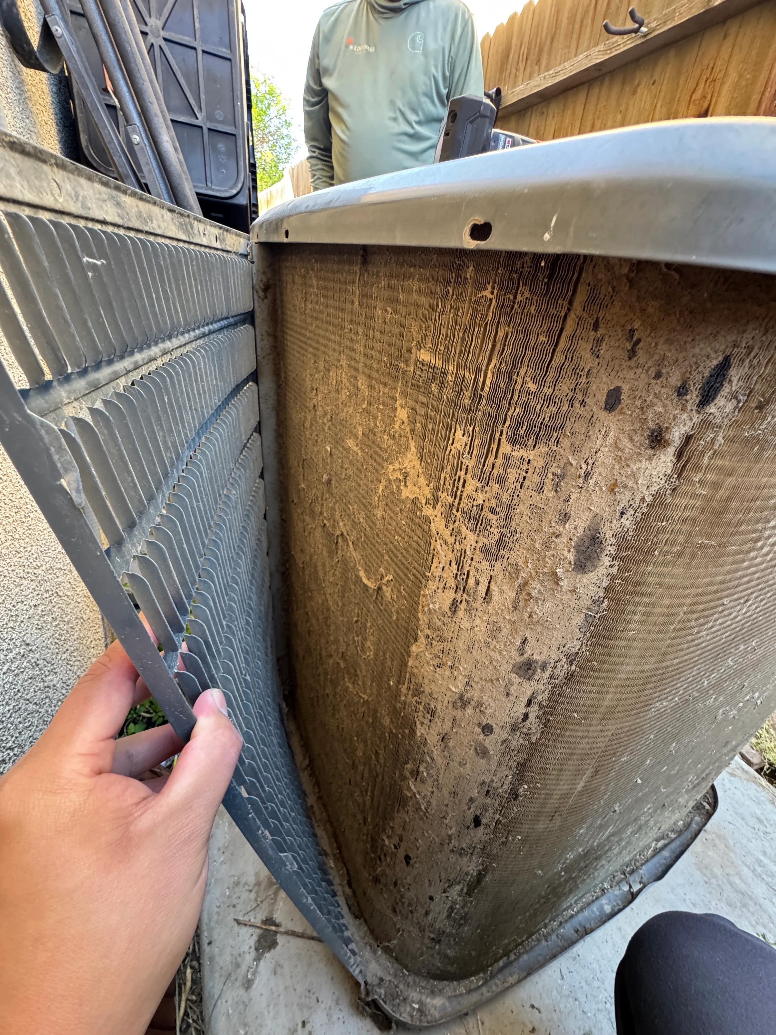 A condenser coil matted with Bakersfield valley dust before cleaning at a Comfort Reset visit