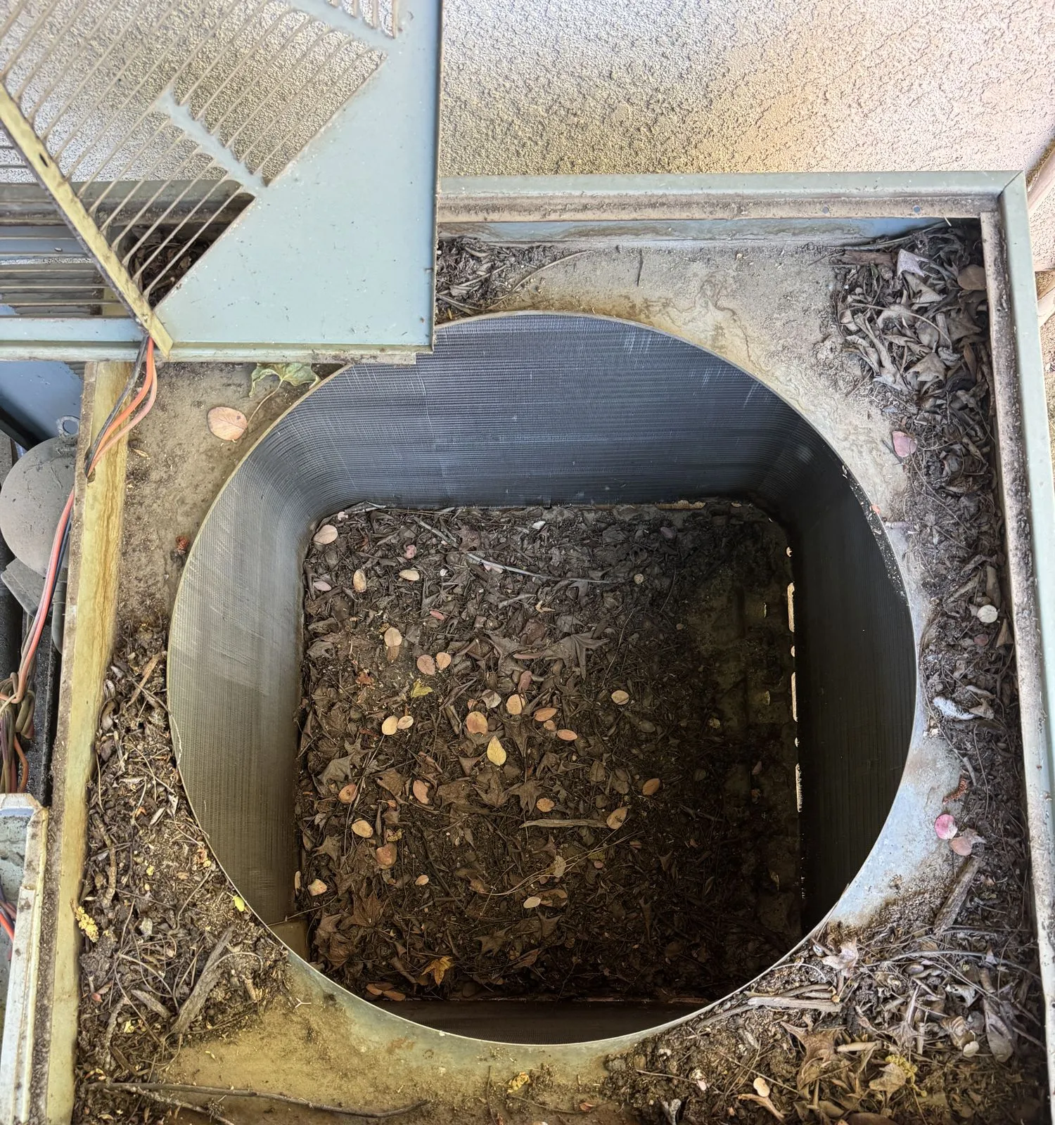 The inside of a Bakersfield condenser cabinet packed solid with dead leaves and debris, found during a service call