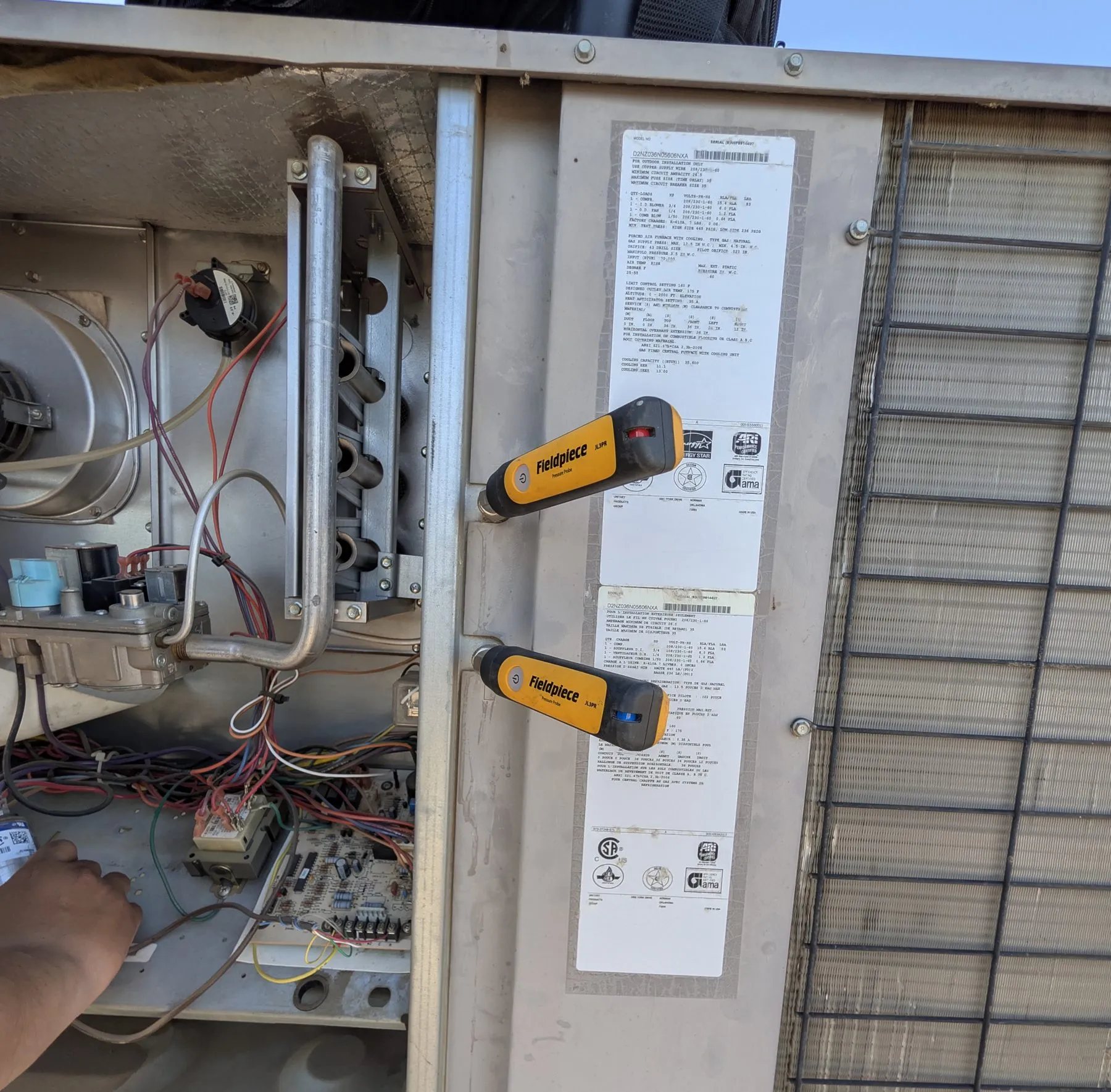 Pressure probes reading a gas package unit during a Wildflower Climate diagnostic in Bakersfield, burners and gas valve open to view