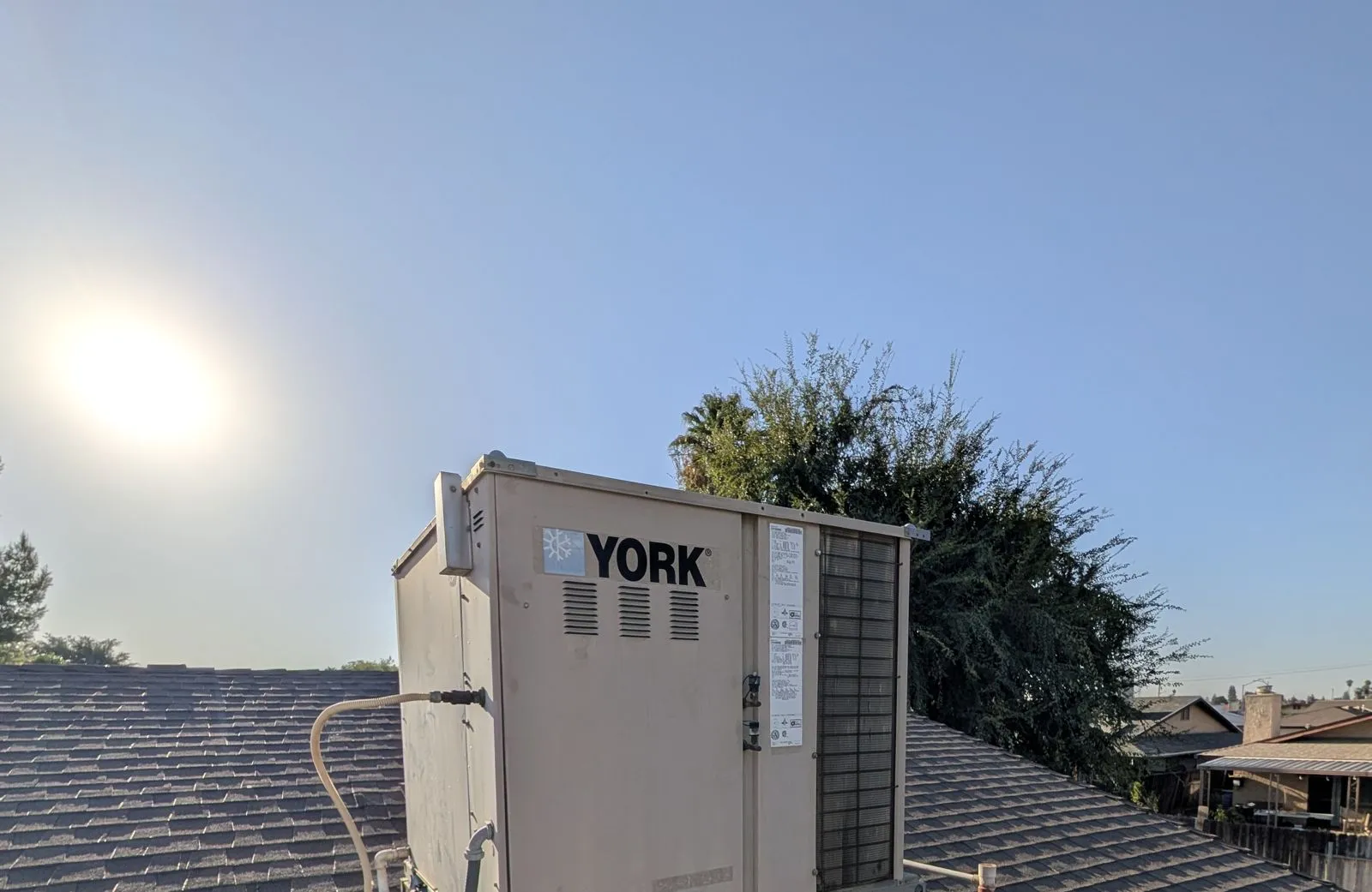 A rooftop package air conditioner on a Bakersfield home photographed at first light during a service call
